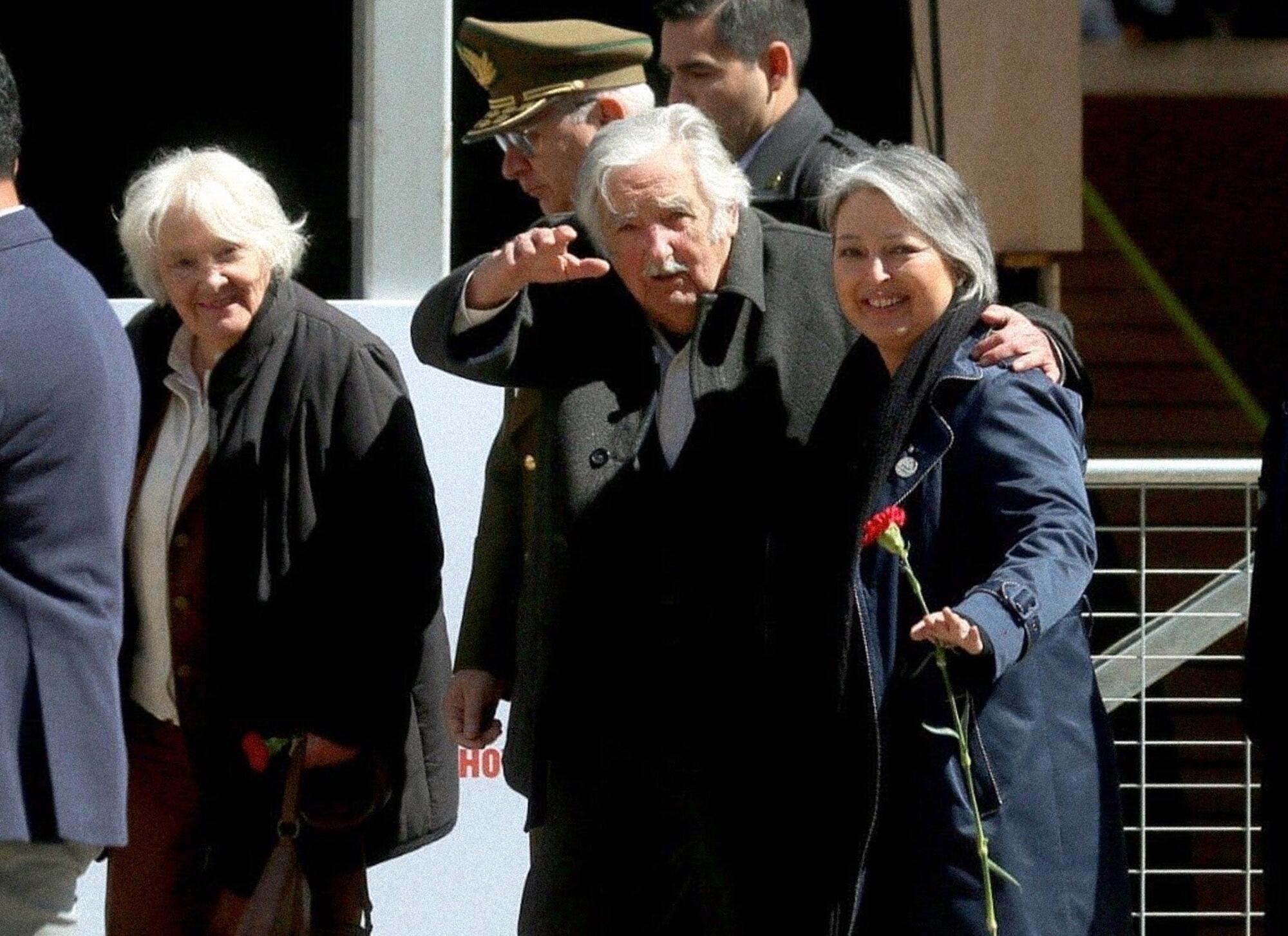 Jeannette Jara, con una flor en la mano, junto con José Mujica.
